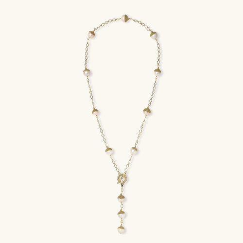 Gold-plated lariat necklace with baroque pearls and textured caps on cream background, showing adjustable Y-shaped design.